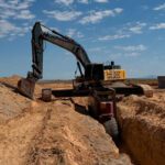 Excavator digging a trench in desert