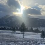 Sunbeams over snowy mountain meadow with pines