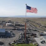American flag flying above industrial storage tanks