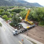 Yellow crane and flatbed truck at construction site