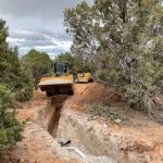 Excavator digging trench for pipe installation
