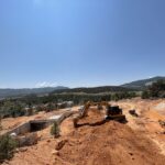 Excavator digging red dirt at mountain construction site