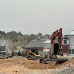 Red excavator digging at farm construction site