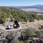 Dump truck dumping soil on forested hillside