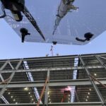 Workers installing large glass panel on building