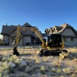 Yellow excavator parked in front of house