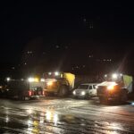 Airport snow removal vehicles on wet tarmac