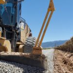 Road grader leveling gravel on rural road