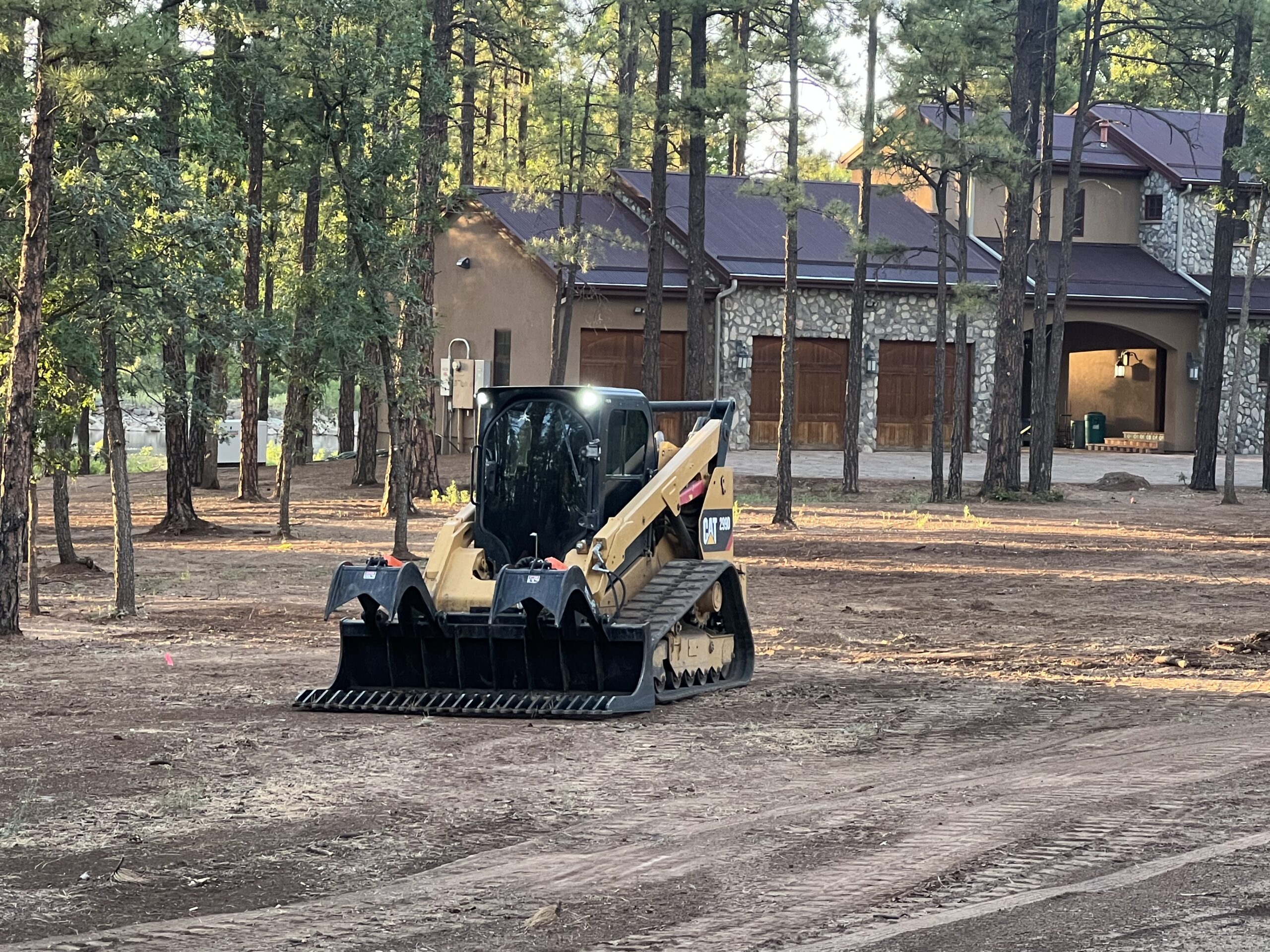 Compact track loader parked near wooded house